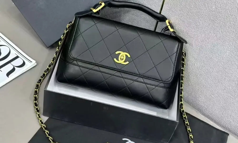 Black quilted handbag with gold chain and CC logo on a gray surface