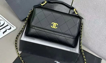 Black quilted handbag with gold chain and CC logo on a gray surface