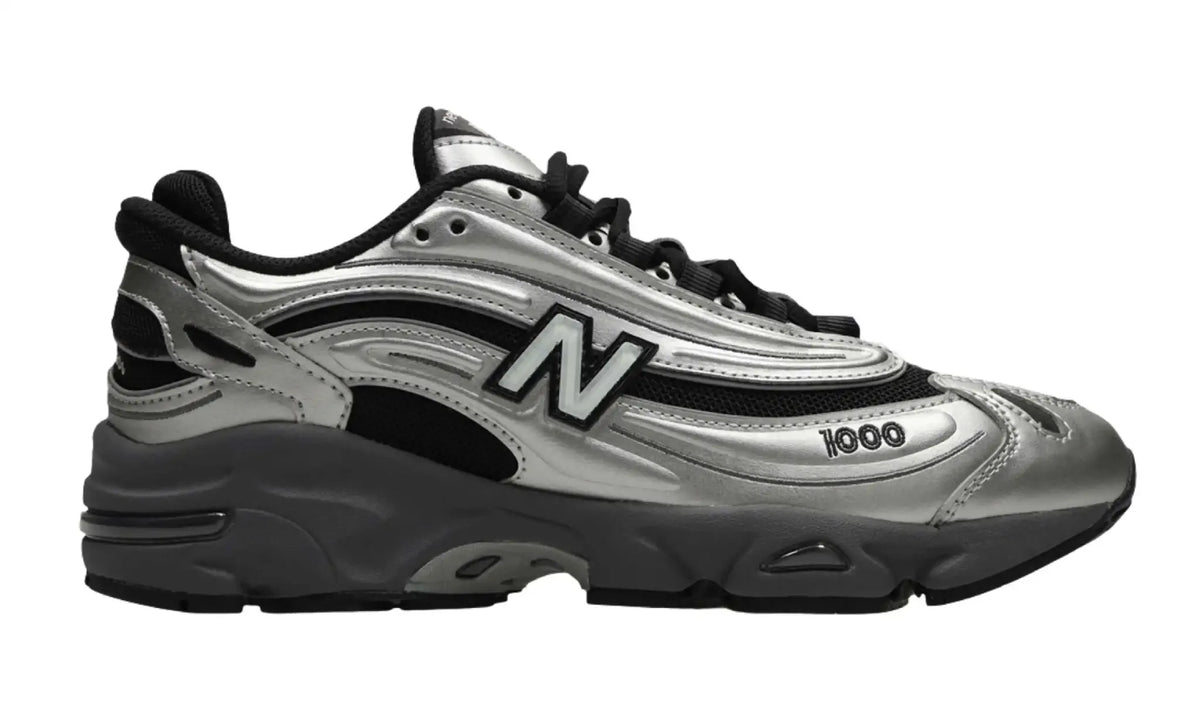 New Balance 1000 unisex sneaker with metallic silver overlays, black mesh-style panels, a large N side logo and a sculpted grey sole