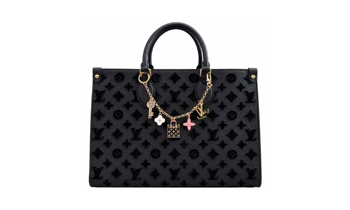 Front view of Black OnTheGo MM monogram tote bag with gold-tone charm chain and top handles